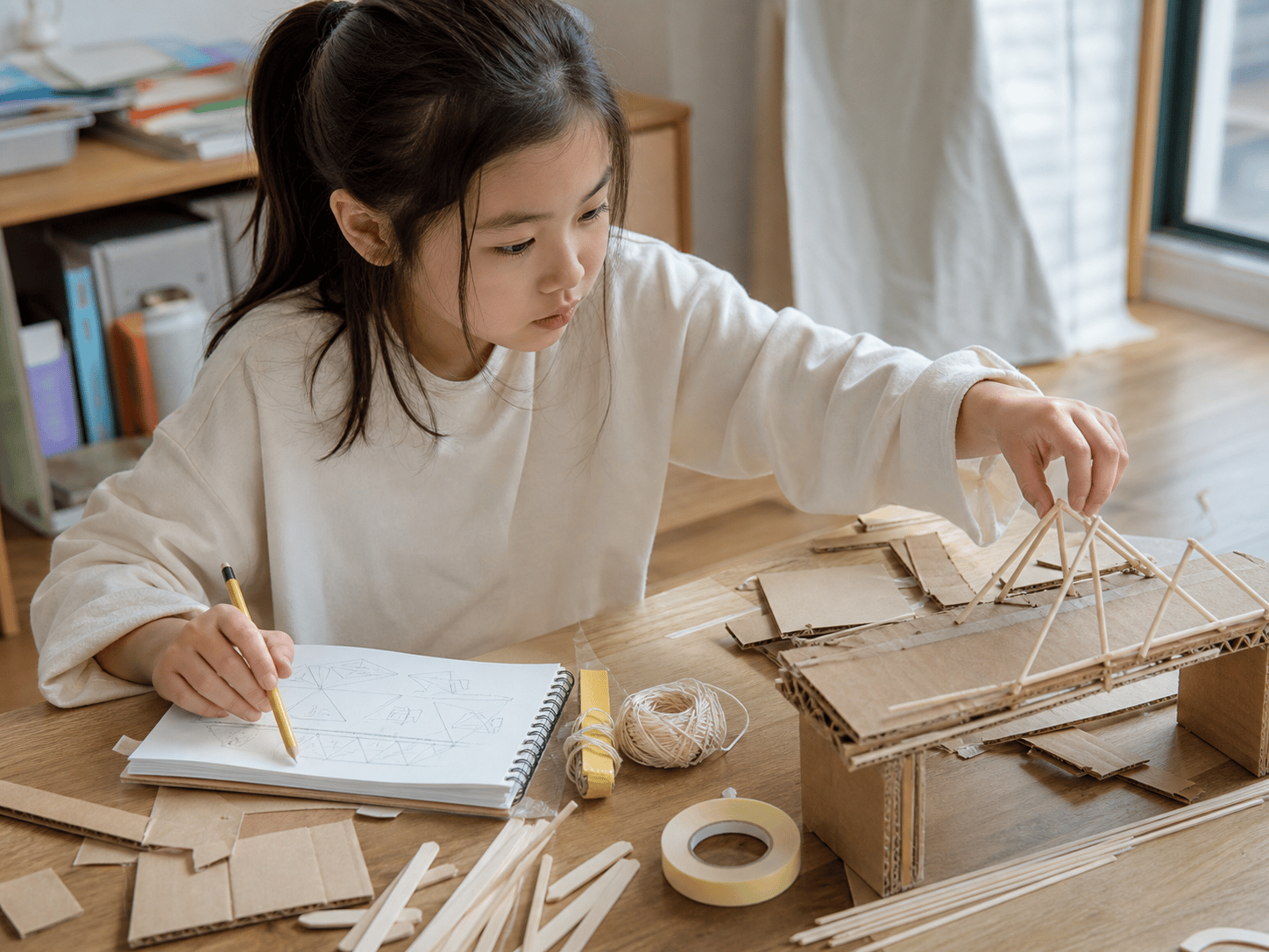 Trẻ em vẽ thiết kế và xây mô hình bằng que gỗ cùng bìa carton.